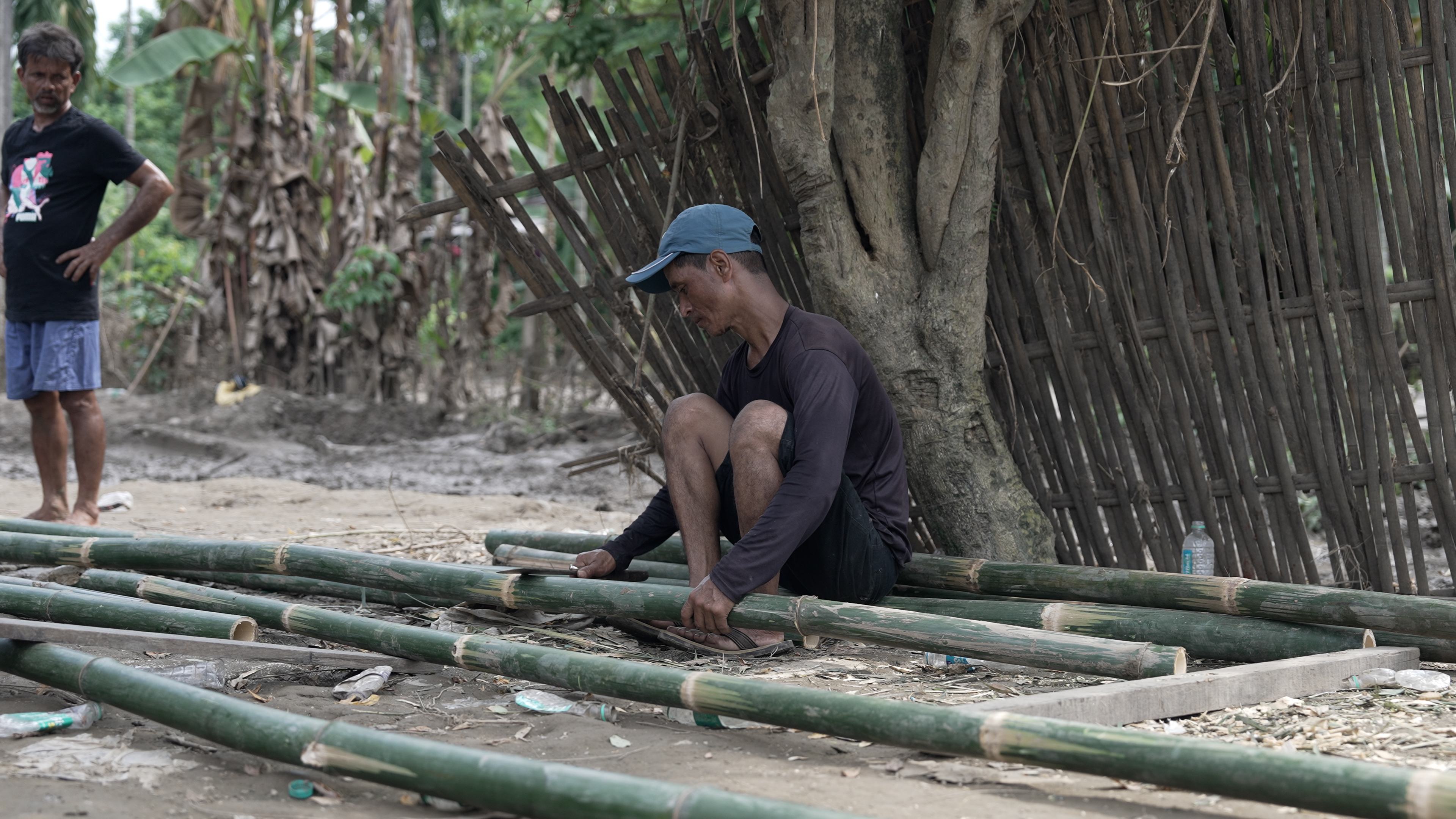 A volunteer splitting bamboo to frame a new house in Assam